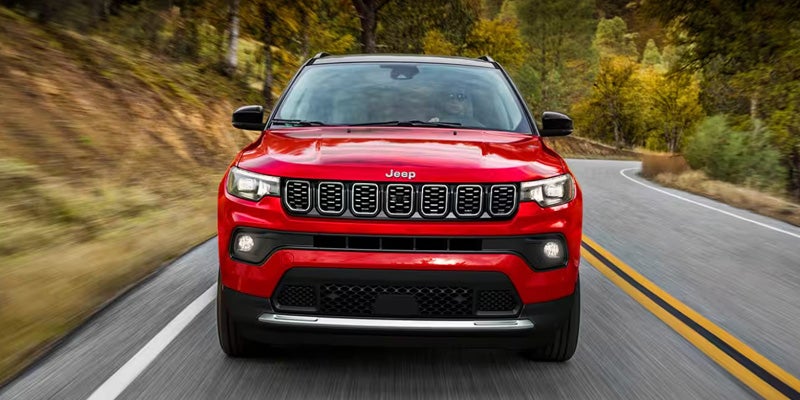 a red 2025 Jeep Compass driving up a highway