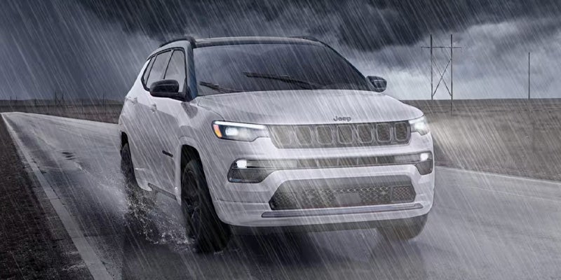 a white 2025 Jeep Compass driving in the rain
